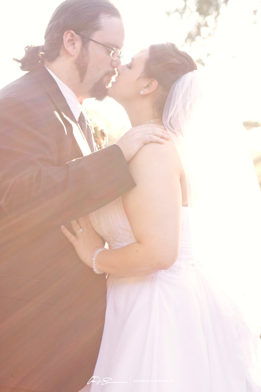 Bride and groom kiss in sunlight