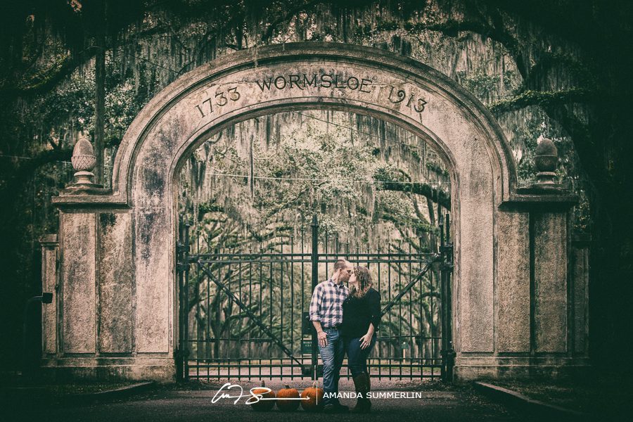 engaged couple poses in front of wormsloe plantation historic site gates