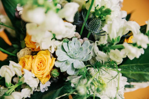 A close-up of a wedding bouquet with succulents and yellow roses