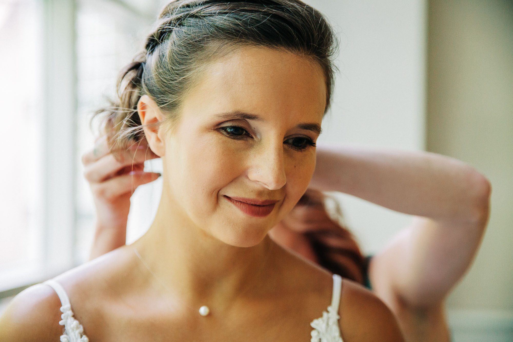 Hey close-up of a bright thoughtful face as her friends help her get dressed on her wedding day