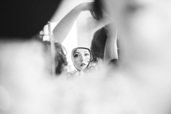 black and white photo of a bride looking into a hand held mirror