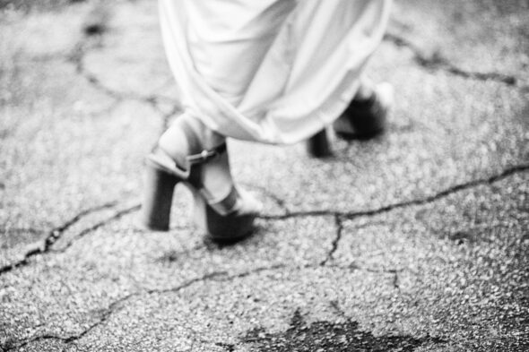 black and white photo of the feet of a bride walking on pavement