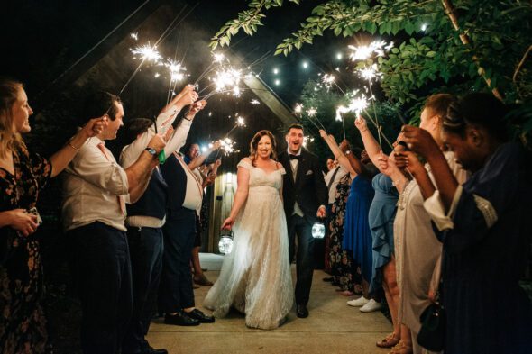 a couple walks through a tunnel of their guests holding sparklers as they leave their wedding at Juliette chapel in dahlonega