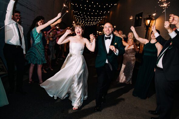 a couple runs through a tunnel of their friends holding sparklers at their wedding at glover park brewery in downtown marietta
