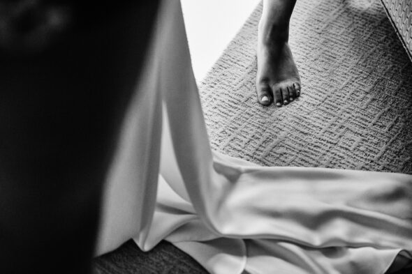 black and white photo of a foot stepping into a wedding dress
