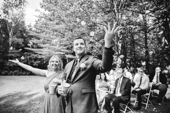 black and white photo of a man and woman throwing flower petals during a wedding ceremony