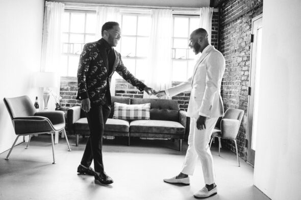 black and white photo of two black grooms joyfully seeing each other for the first time on their wedding day