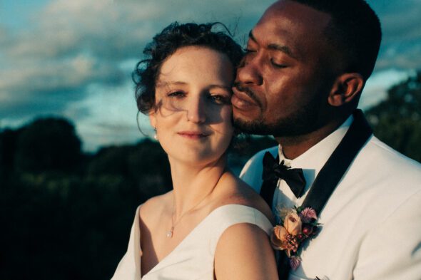 a white bride and a black groom pose for sunset photos on top of historic Rhodes Hall in Atlanta