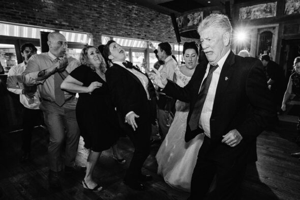 black and white photo of people laughing and dancing at wedding reception