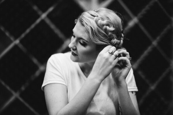 black and white photo of a bride looking to the side while putting on her earrings