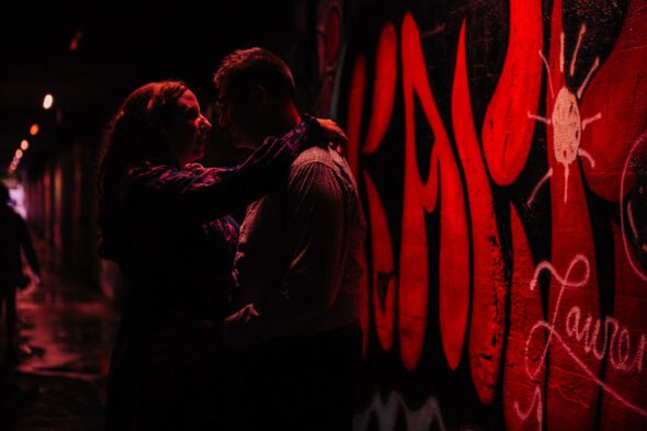 a couple embraces under red light in the Krog Street Tunnel in Atlanta