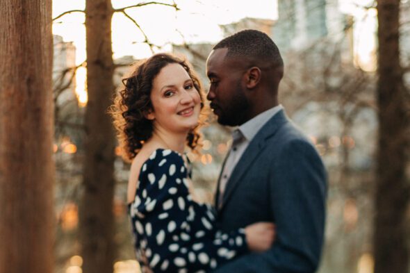 a man and a woman embrace in Piedmont Park at sunset for their engagement photos