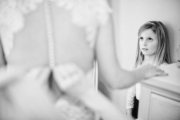 a young girl watches as her mother puts on a wedding dress