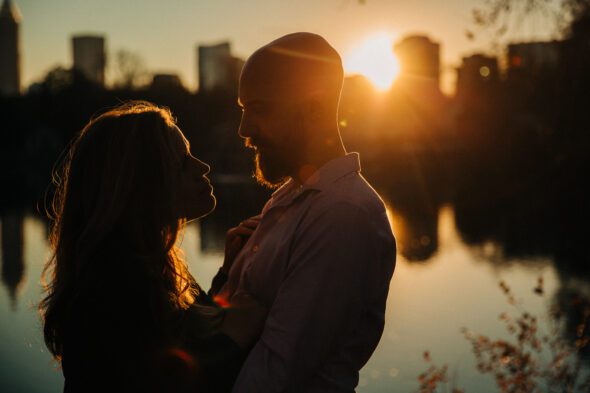 a couple stands facing each other at sunset in front of the atlanta city skyline