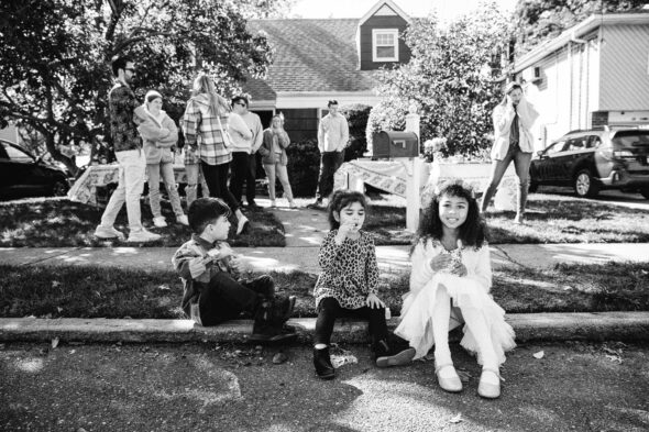 black and white photo of kids sitting on a sidewalk