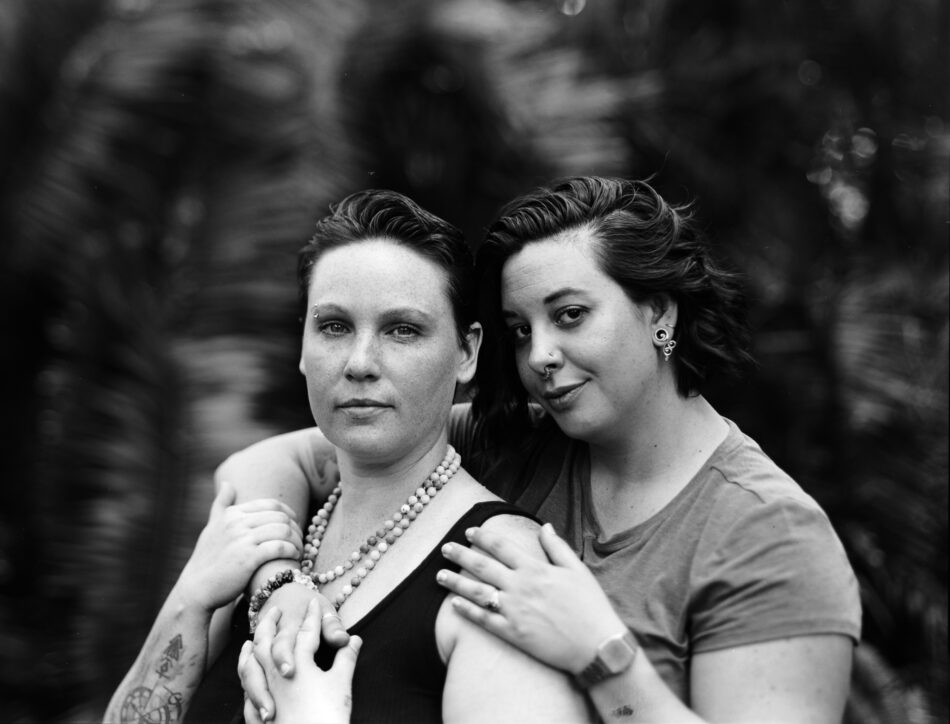 black and white film photo of engaged lgbtq  couple in tropical garden
