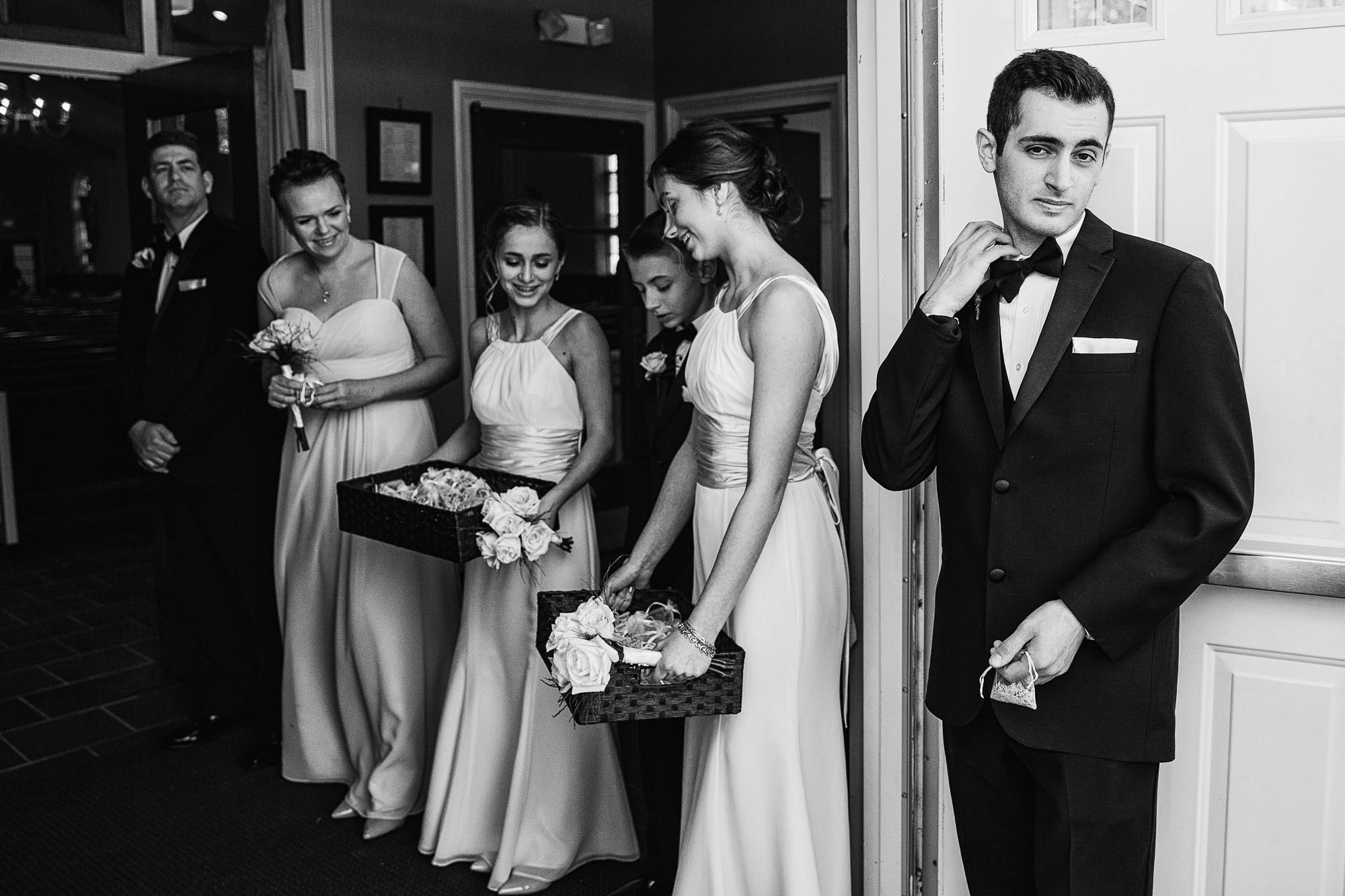 an usher at a wedding adjusts his collar in documentary photo