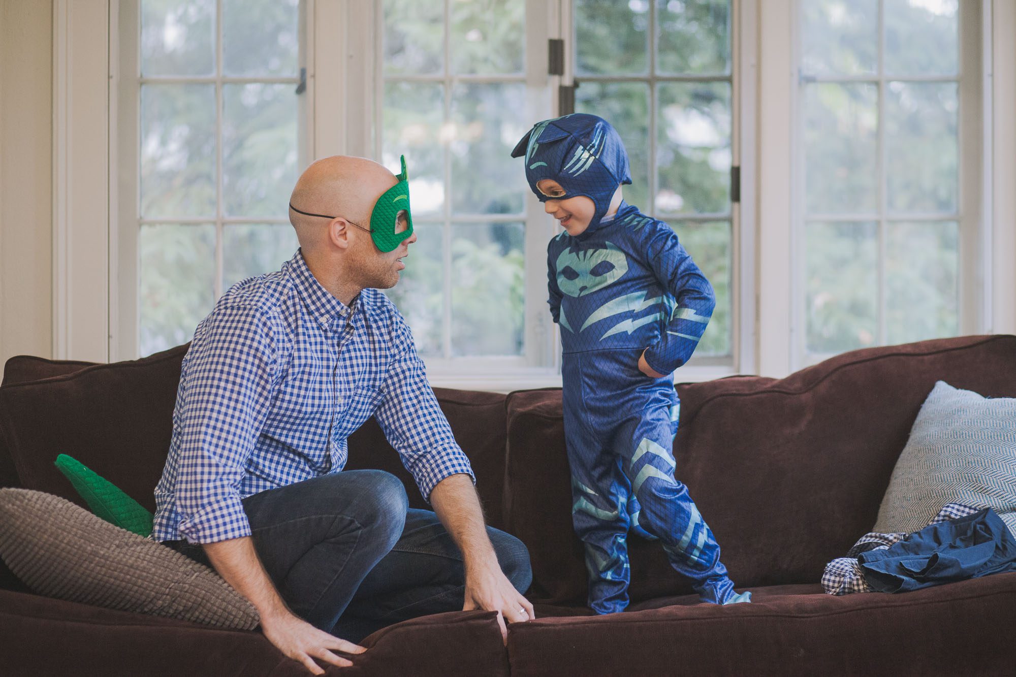 a father and son wearing costumes play together in their living room