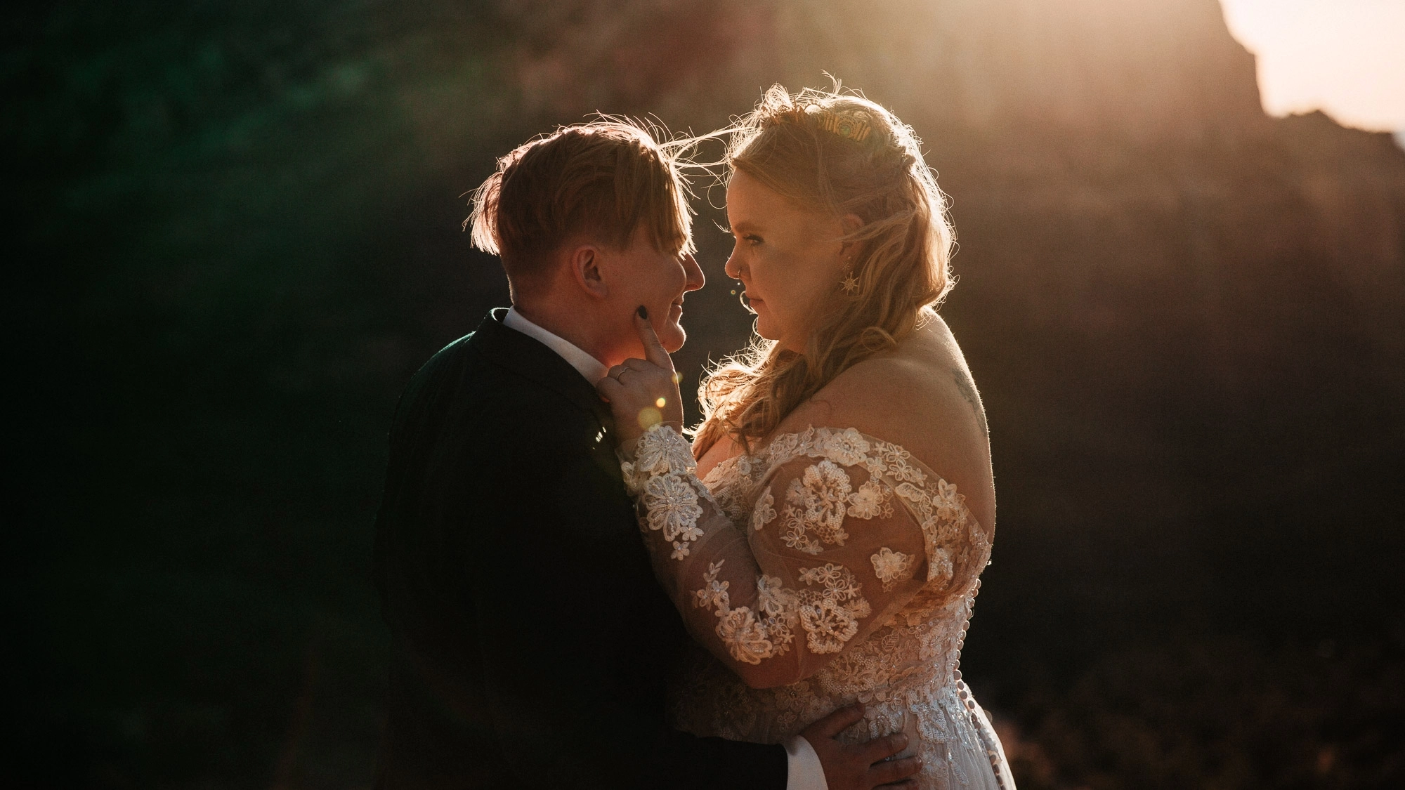 A newlywed couple faces each other in the sunset