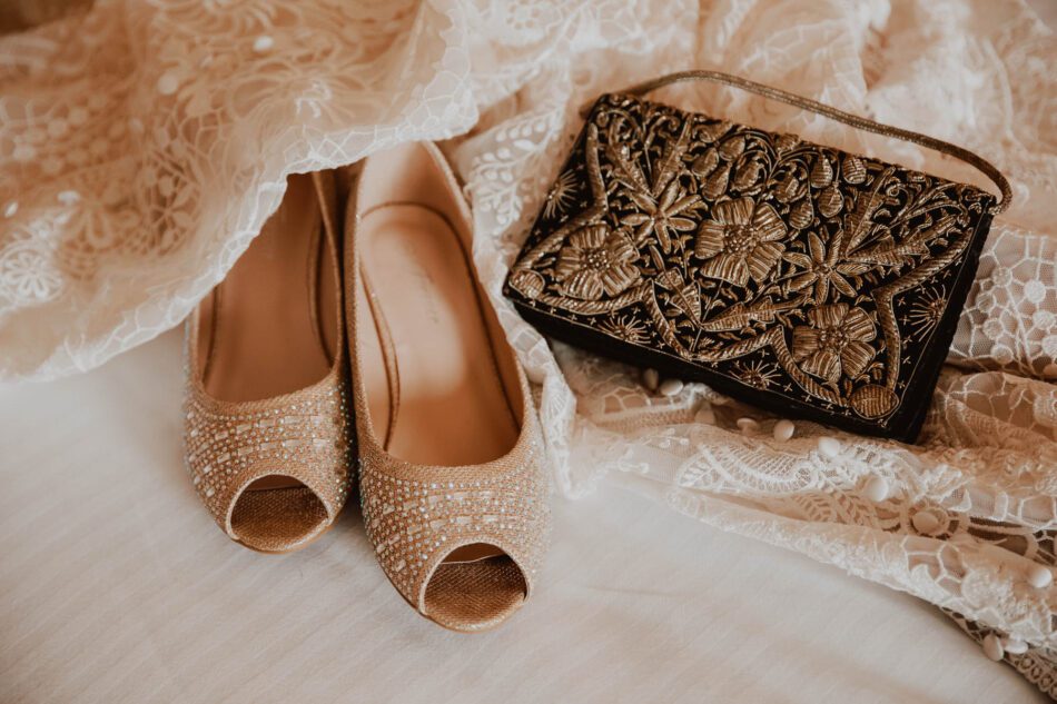 a bride's wedding gown shoes and purse lie on a hotel bed
