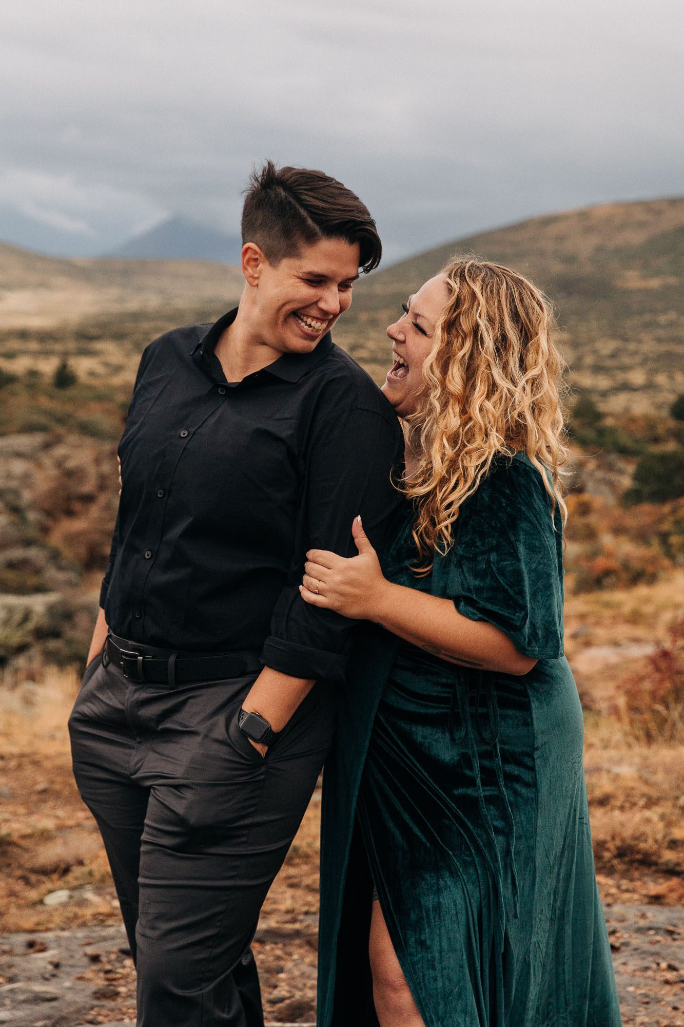 LGBTQ couple embraces in front of a distant mountain for their Colorado engagement photos