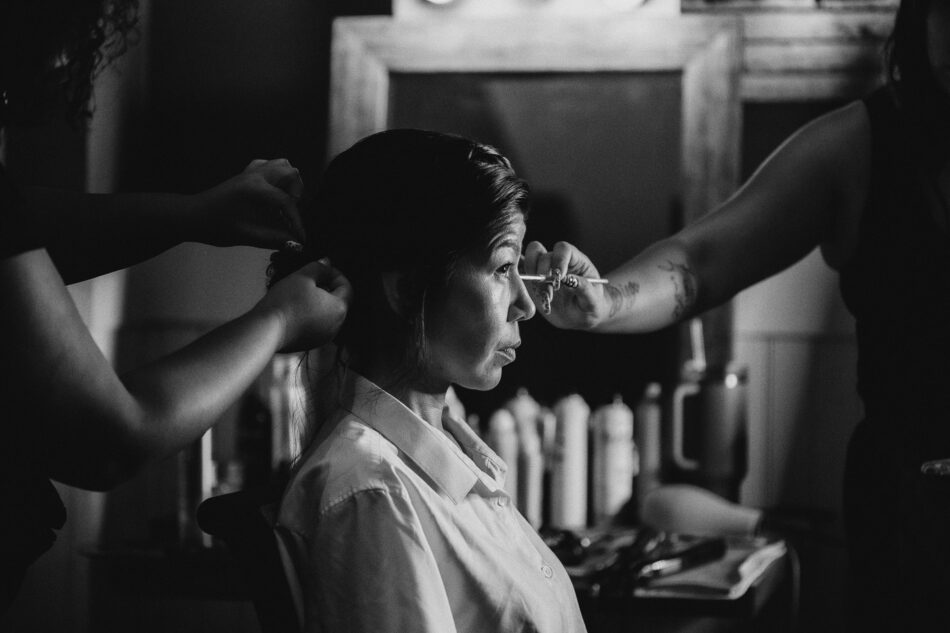 black and white photo of a bride getting her makeup done for her wedding day