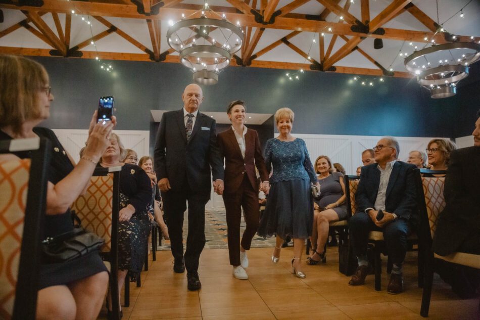 a mother and father walk their daughter down the aisle during an LGBTQ wedding ceremony in Virginia