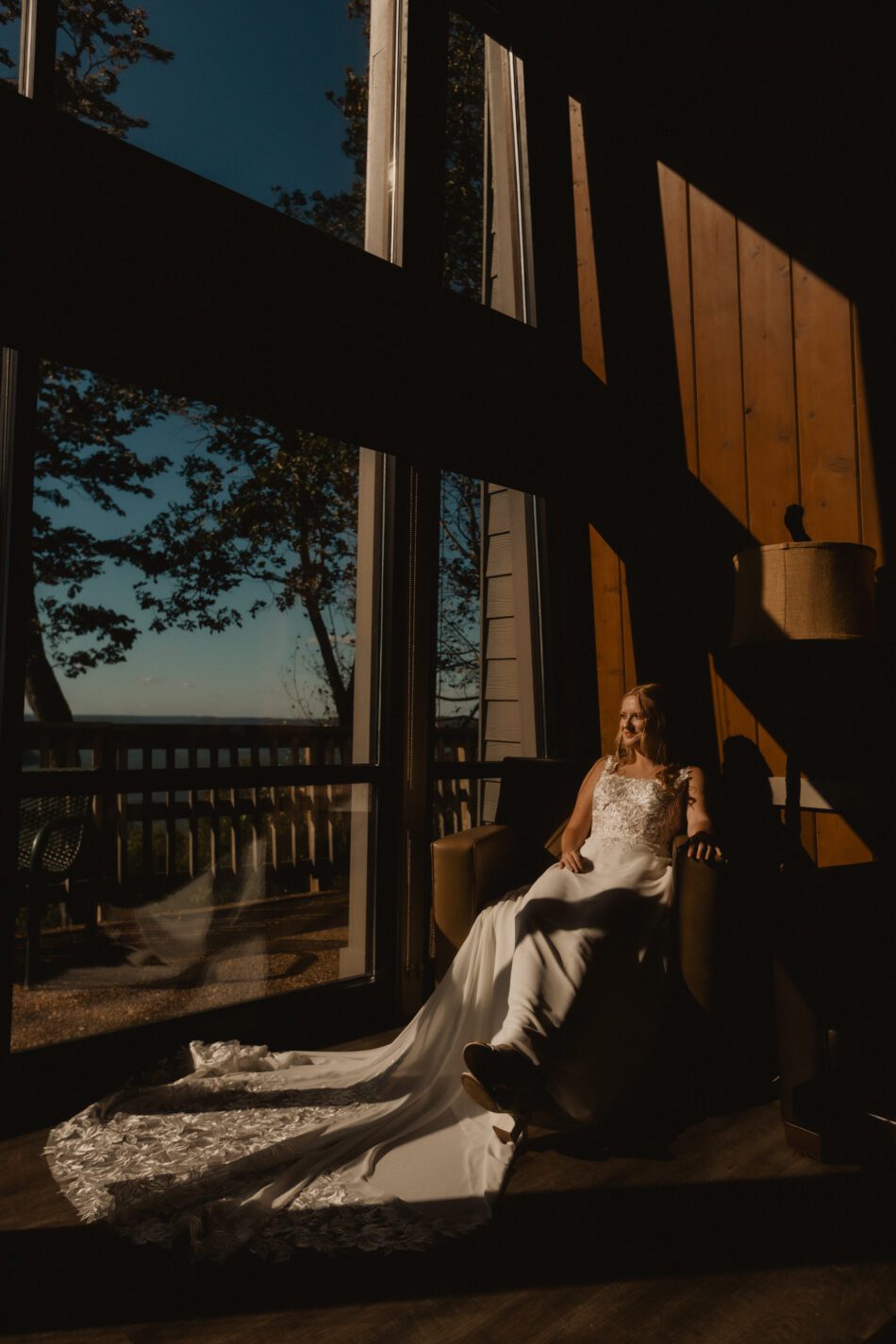bride wearing white wedding dress sits in chair at guntersville state park chalet