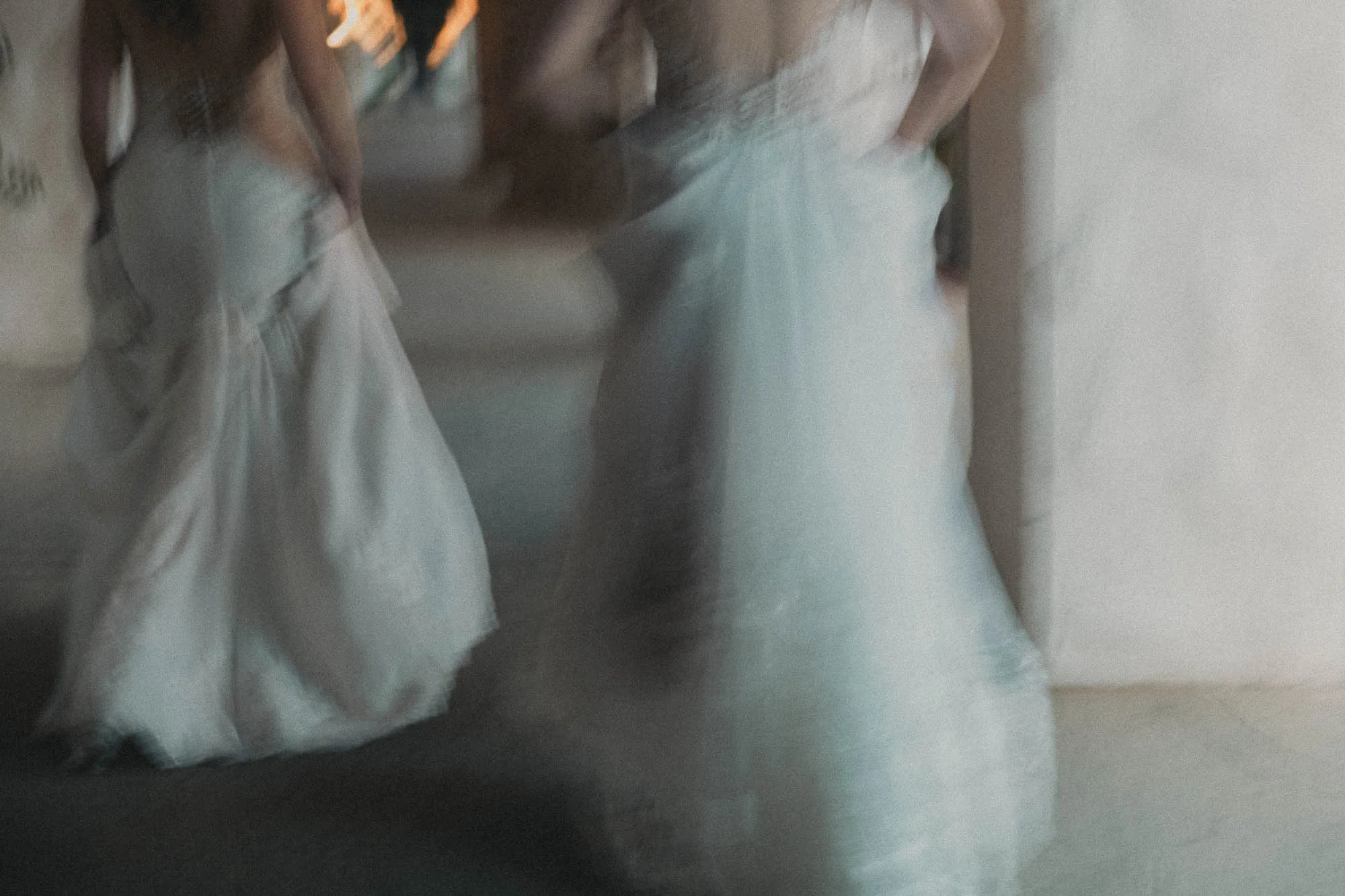 two brides in white dresses walk away from the viewer in a photo blurred by motion