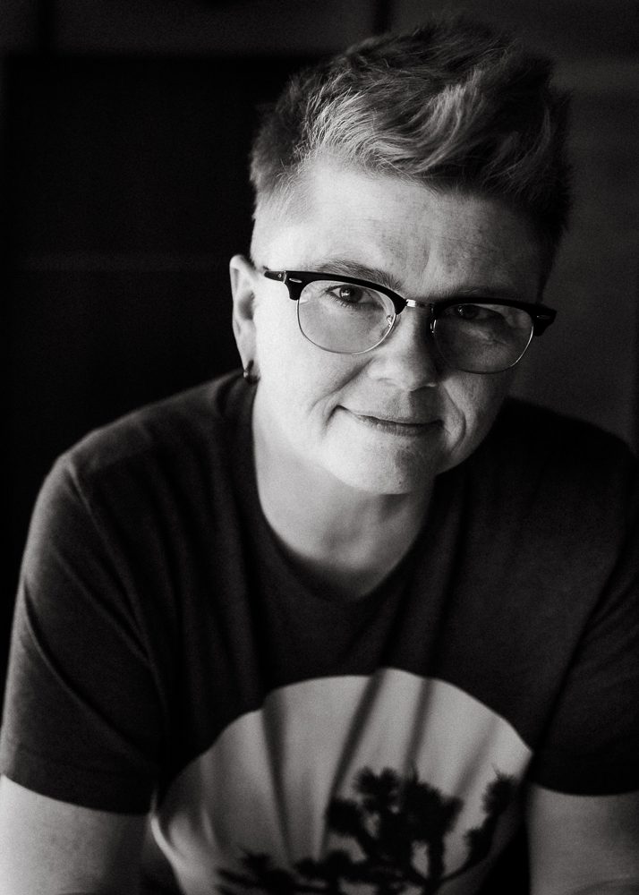 black and white photo of the face of the nonbinary Atlanta wedding photographer Amanda Summerlin wearing horn rim glasses and looking directly at the camera