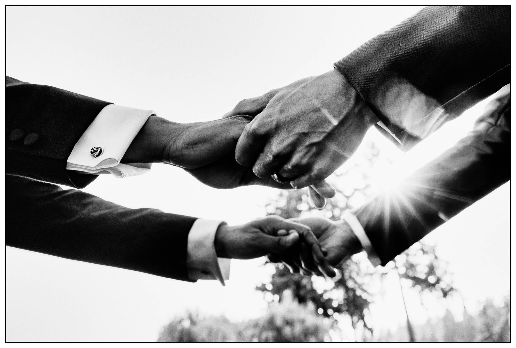black and white photo by atlanta wedding photographer of two grooms holding hands