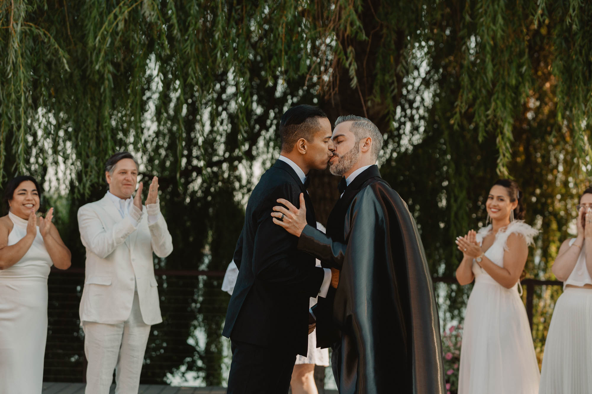 two grooms share their first kiss at their outdoor wedding ceremony