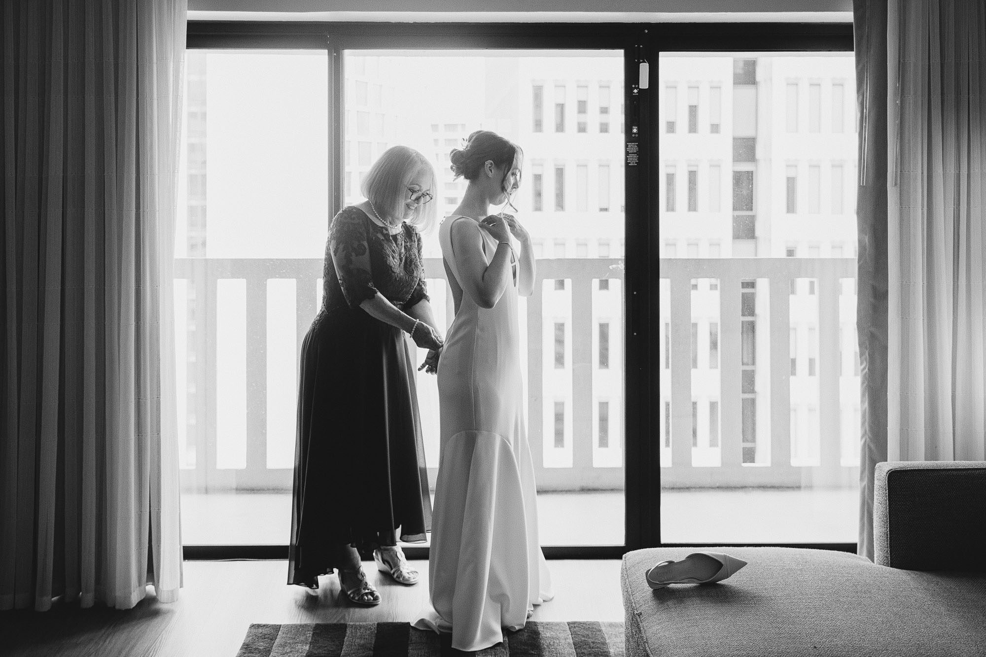 black and white photo by Atlanta documentary wedding photographer Amanda Summerlin of a mother helping her daughter into her wedding dress while getting ready at the Hyatt Regency in Atlanta