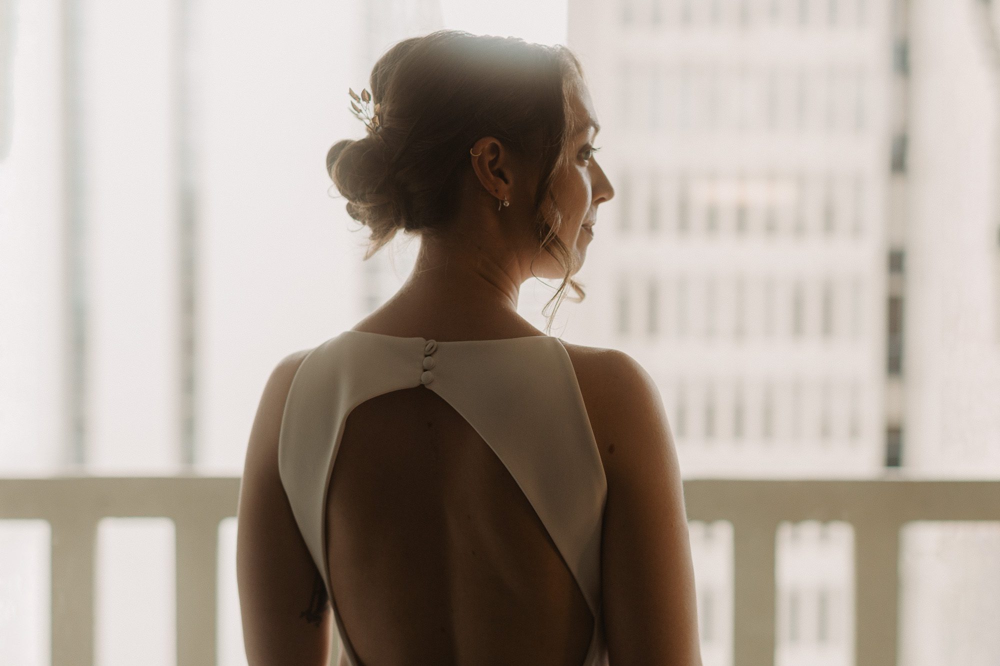 a bride wearing an elegant white wedding dress stands in front of the balcony at the Hyatt Regency Atlanta on her wedding day