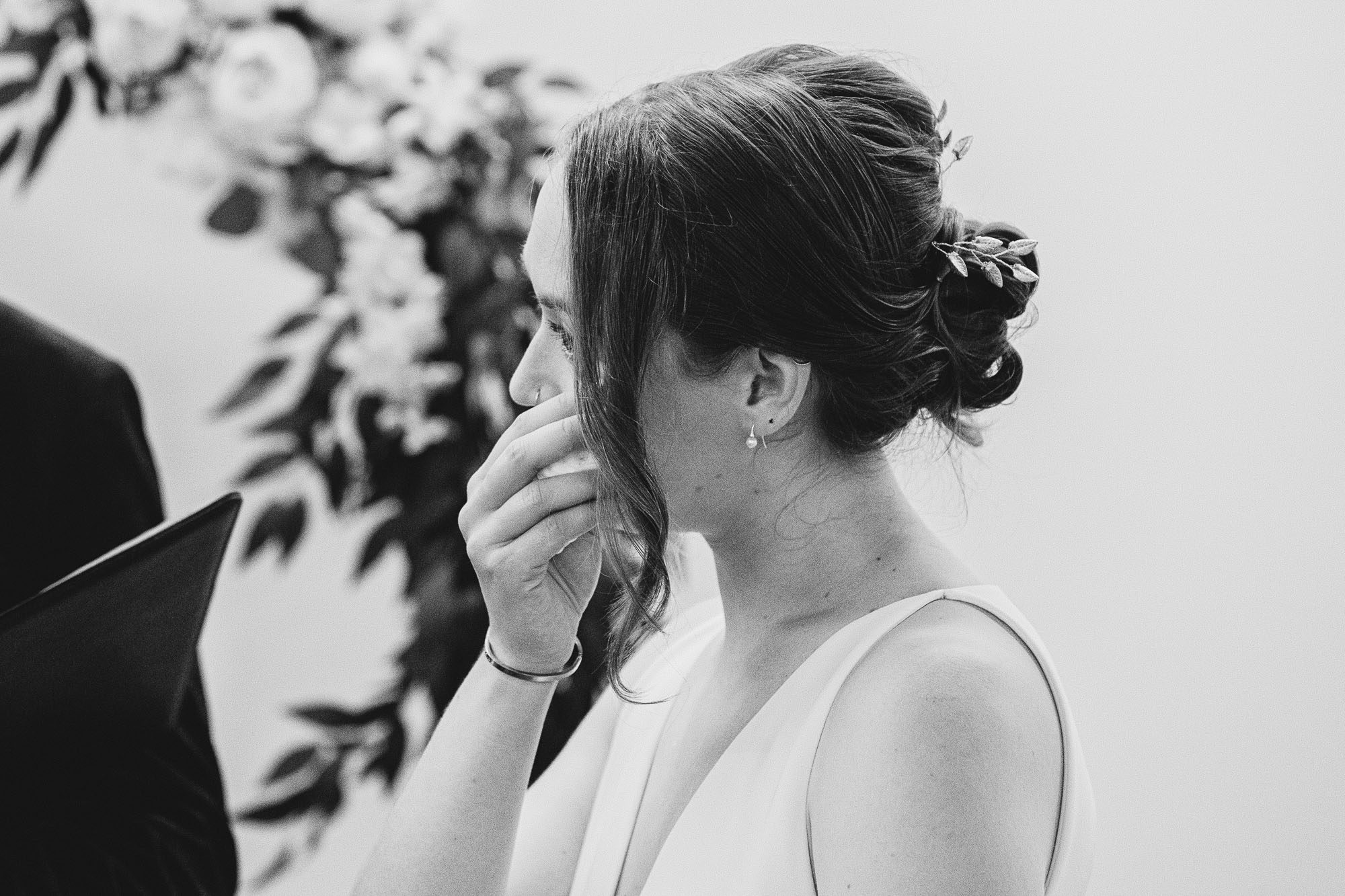 a bride wipes a tear in a black and white documentary photo of an indoor wedding ceremony at the Atlanta Contemporary