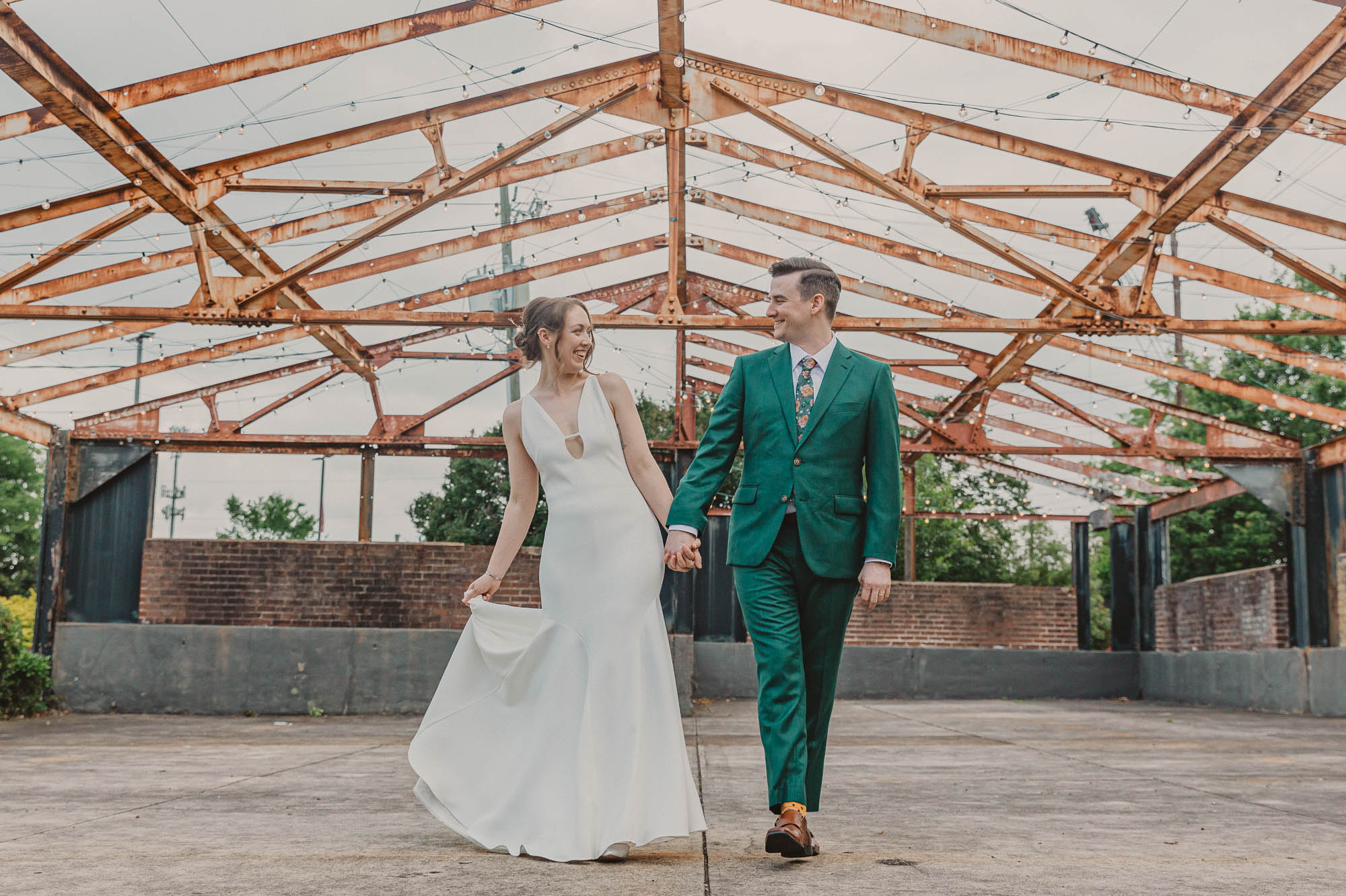 a bride and groom walk hand in hand across the pavilion at the Atlanta Contemporary on their wedding day in atlanta