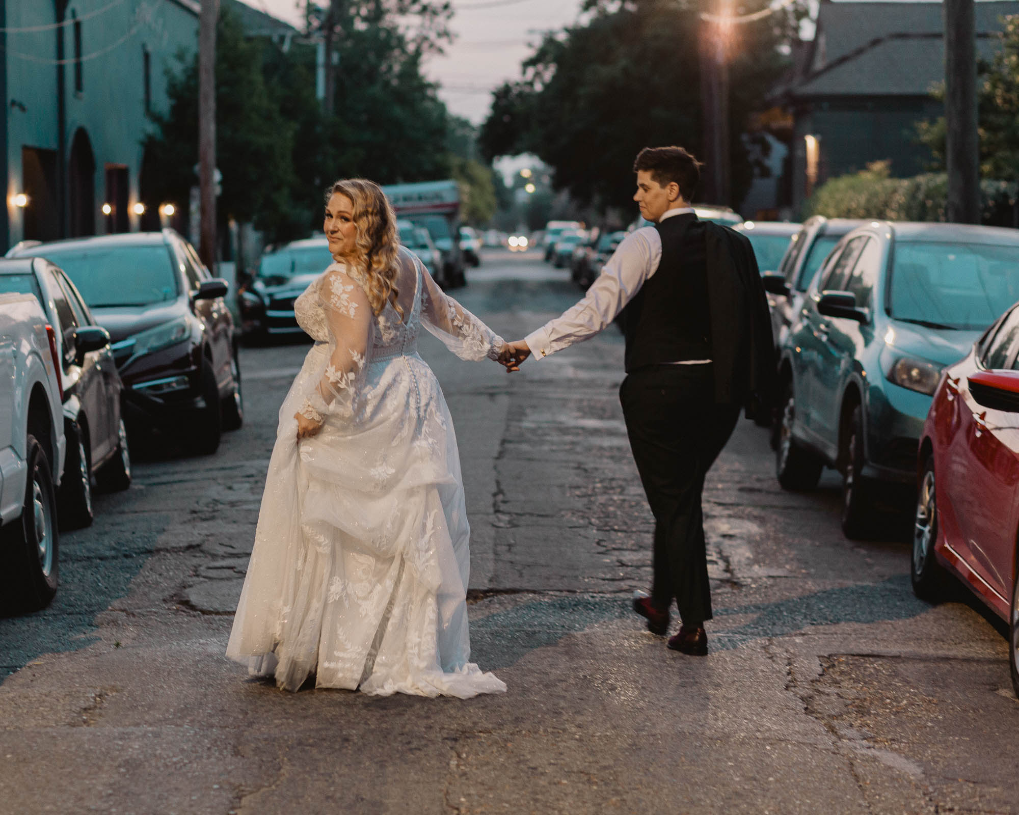 a beautiful queer couple walks hand in hand down the street into the sunset in New Orleans on their wedding day