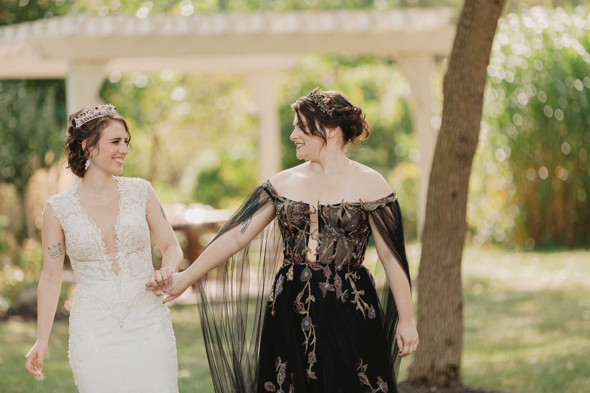 a bride wearing a white wedding dress and a bride wearing a black wedding dress see each other for the first time on their wedding day at their first look