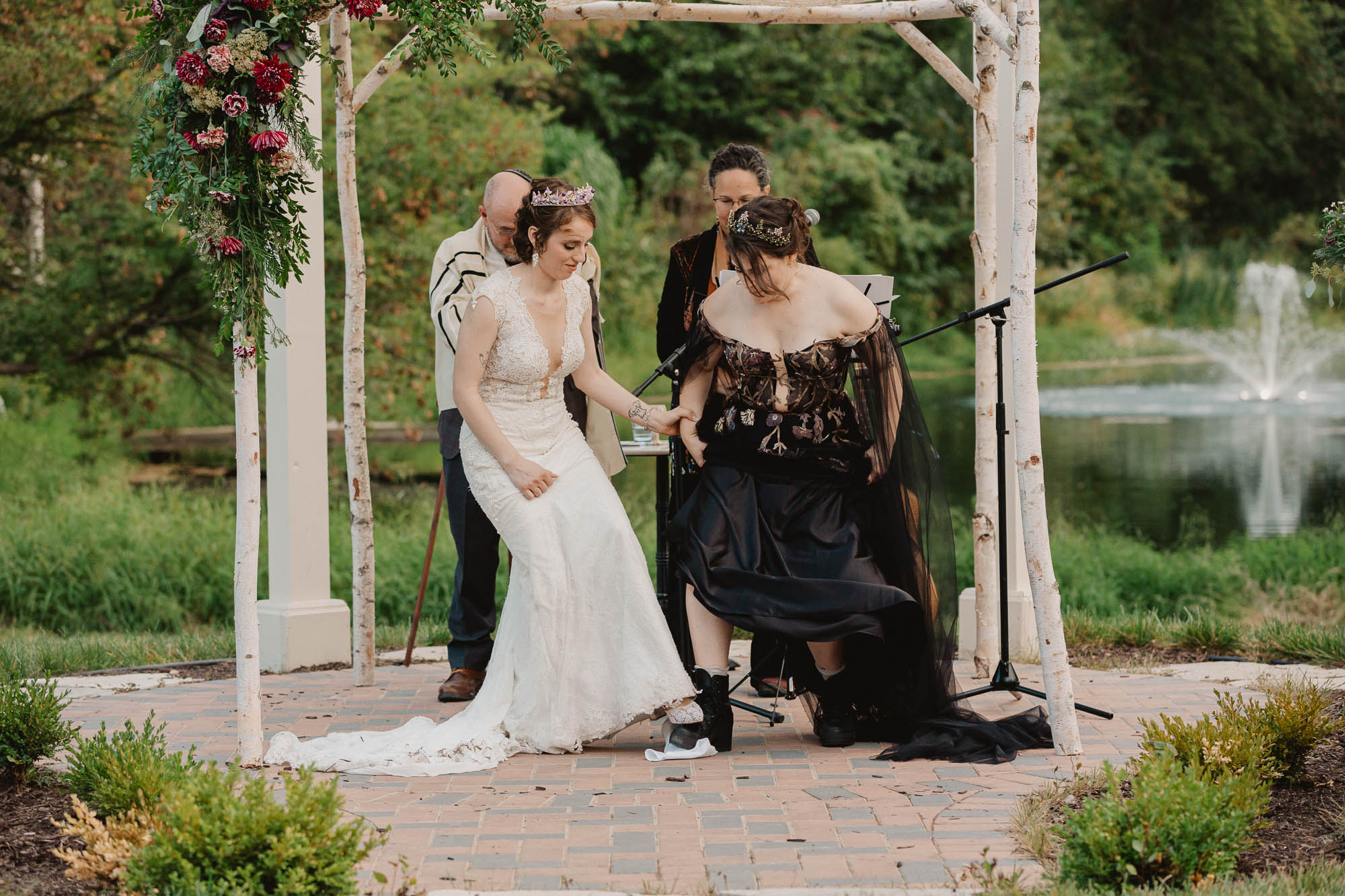 two brides step on a glass at the end of their jewish wedding ceremony