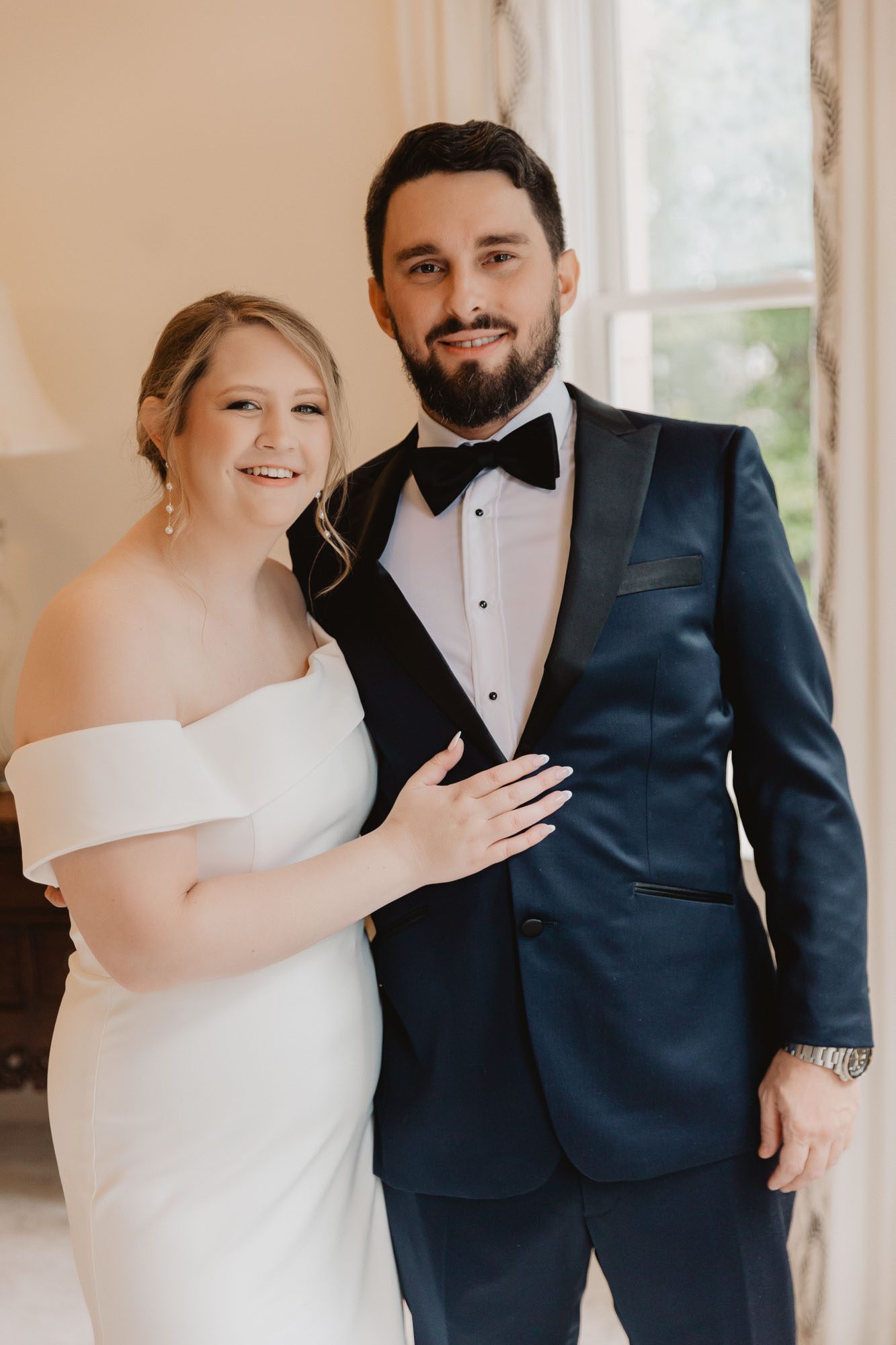 A bride and a groom stand together in the window of Atlanta's historic Wimbish house on their wedding day