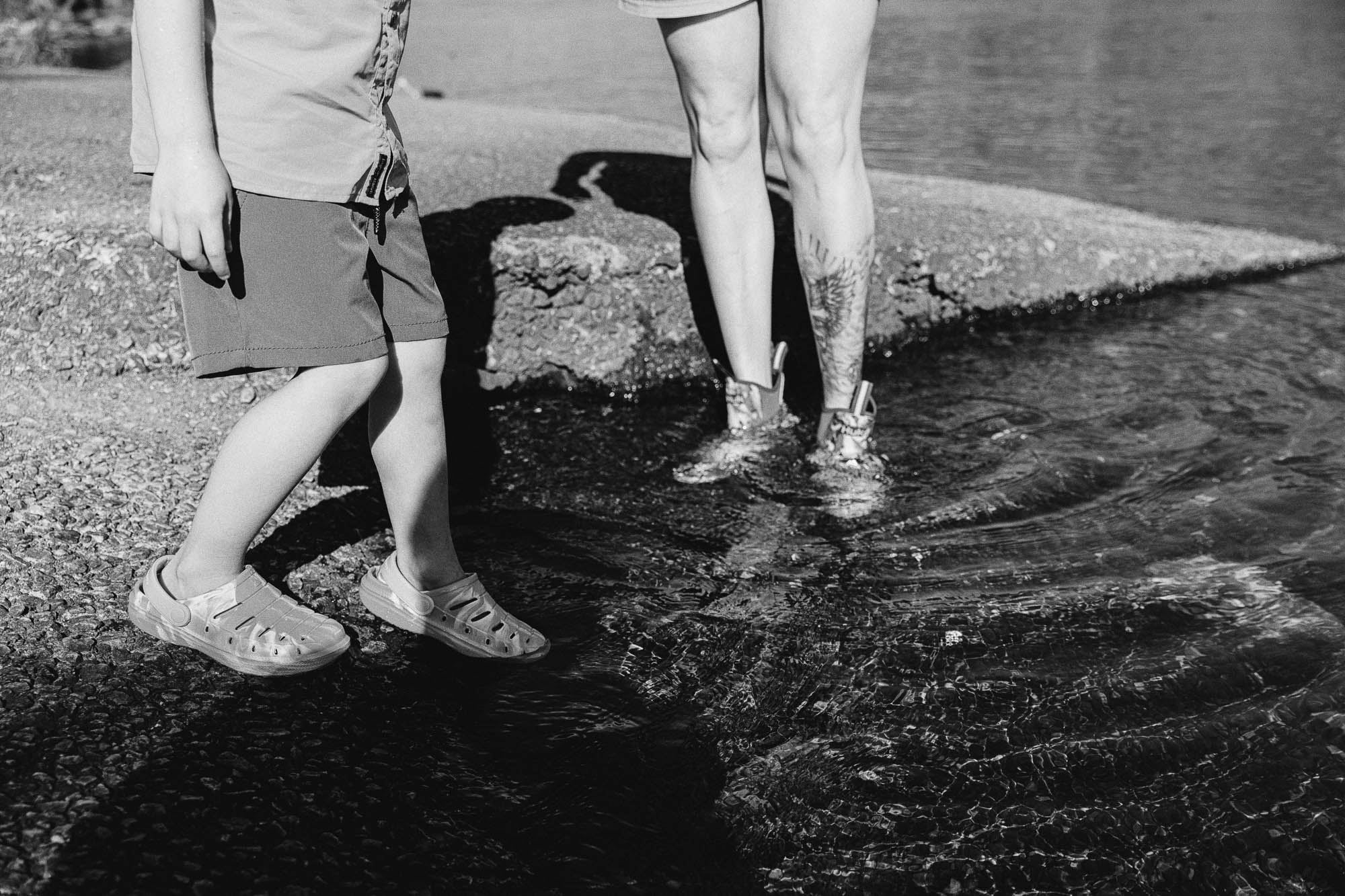 the feet of a small child wearing shorts and an adult wearing shorts standing in the Chattahoochee river during their lifestyle family photo session