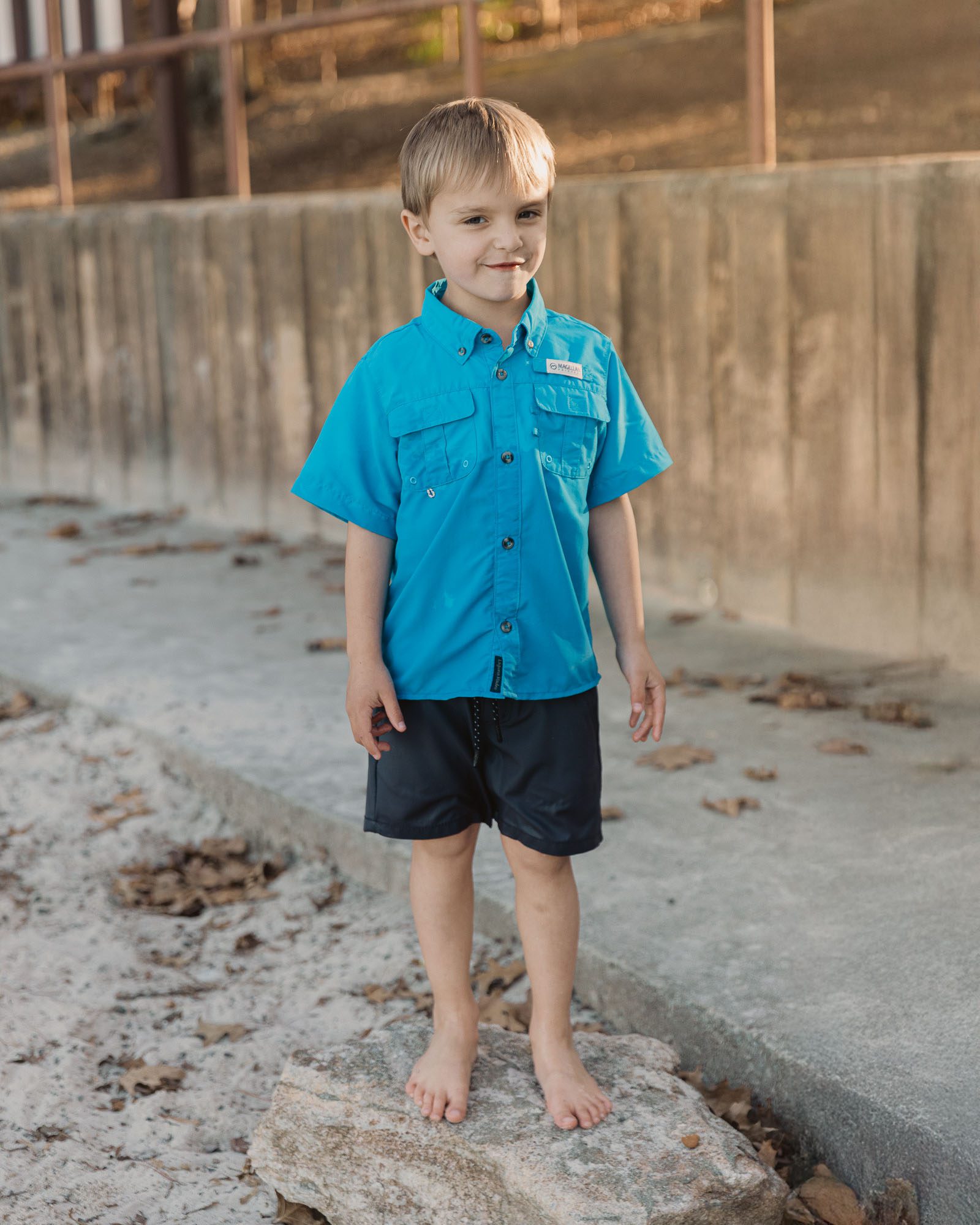 a small child stands and poses on the beach at Lake Lanier during a lifestyle family photo session