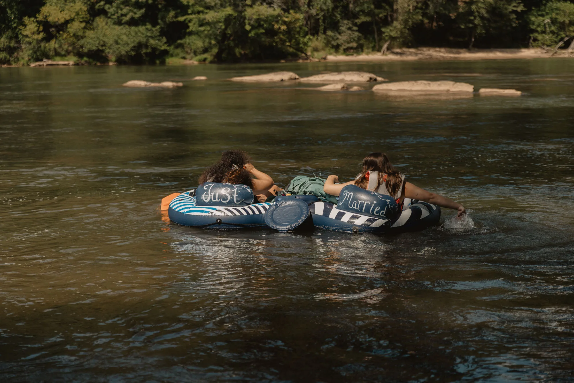 two brides wearing white raft down the river after their wedding day in the bamboo forest on the chattahoochee river in atlanta