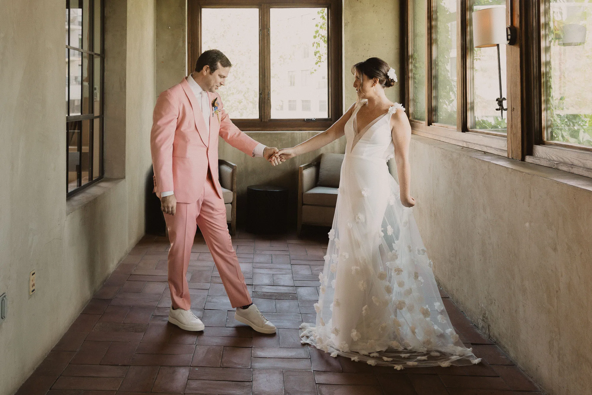a bride wearing a white dress and a groom wearing a pink tuxedo see each other for the first time on their wedding day at Summerour Studio in Atlanta